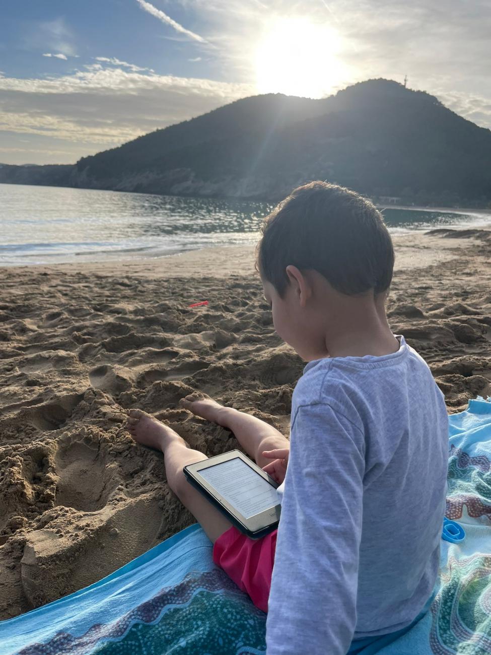 Boy reading on beach